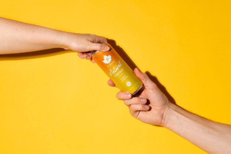 Puhdistamon energiajuomatölkki, josta pitää kiinni kaksi kättä kummastakin sivusuunnasta.